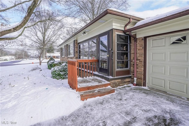 snow covered property entrance featuring a garage