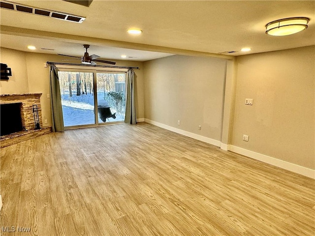 unfurnished living room featuring ceiling fan, a fireplace, baseboards, and light wood-style floors