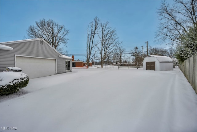 yard covered in snow featuring a garage and a storage unit