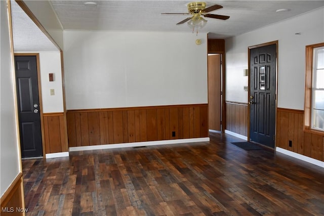 foyer featuring ceiling fan, dark wood-type flooring, and wooden walls