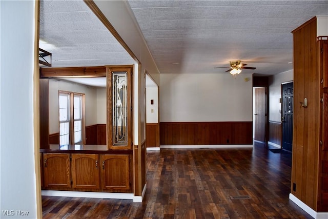 corridor with dark wood-type flooring, wood walls, and a textured ceiling