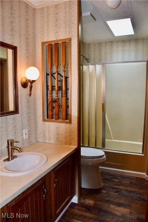 full bathroom featuring toilet, vanity, hardwood / wood-style flooring, tub / shower combination, and a skylight