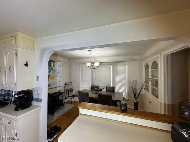 interior space with dark wood-type flooring, an inviting chandelier, white cabinetry, and decorative light fixtures