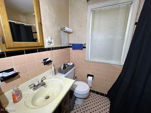 bathroom with toilet, tile walls, tile patterned floors, and vanity