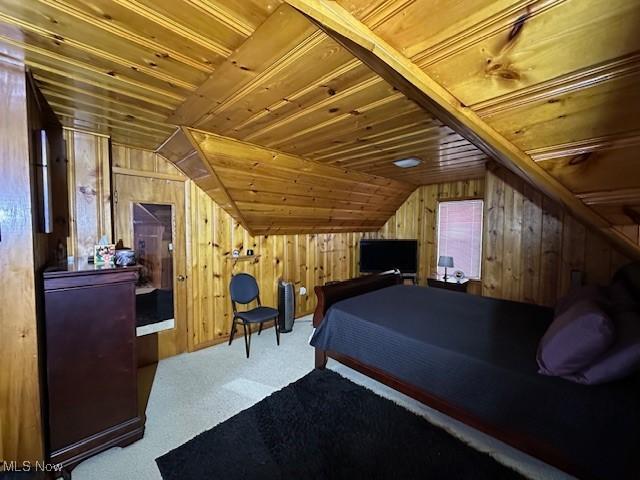 bedroom featuring vaulted ceiling, wood ceiling, wood walls, and carpet floors