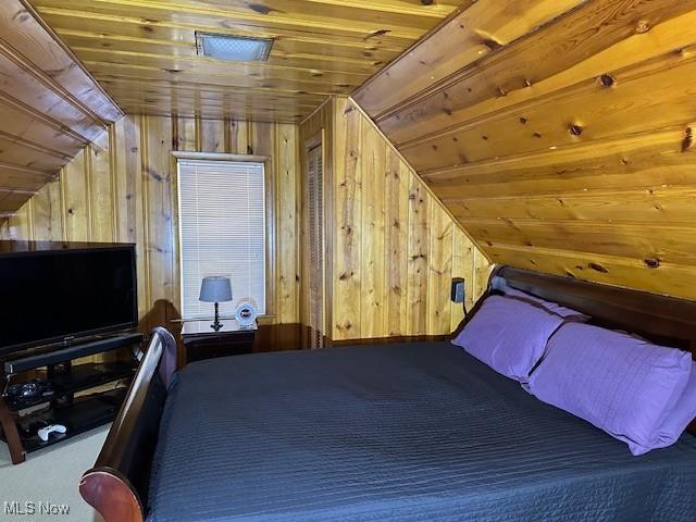 unfurnished bedroom featuring carpet, vaulted ceiling, wood ceiling, and wood walls