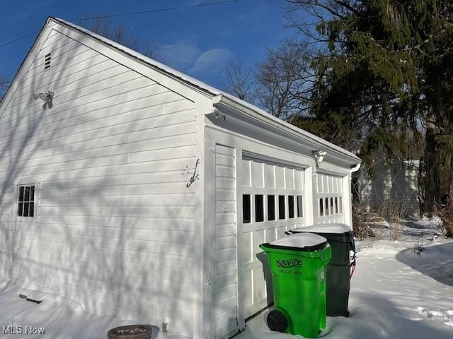 snow covered property with an outbuilding and a garage