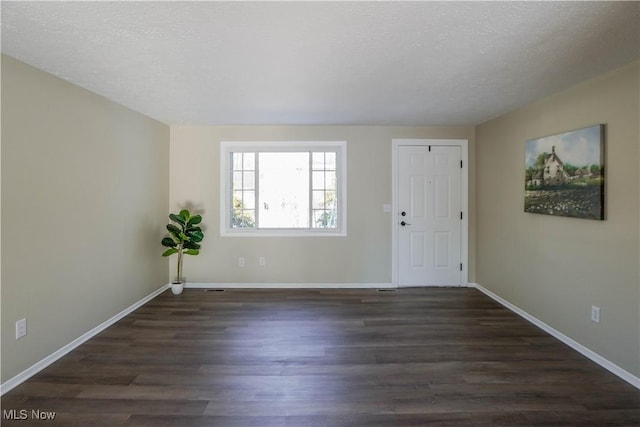 empty room featuring a textured ceiling and dark hardwood / wood-style flooring