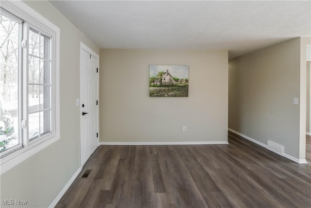 spare room with dark hardwood / wood-style flooring and a textured ceiling