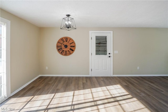 spare room featuring a notable chandelier, a textured ceiling, and hardwood / wood-style floors