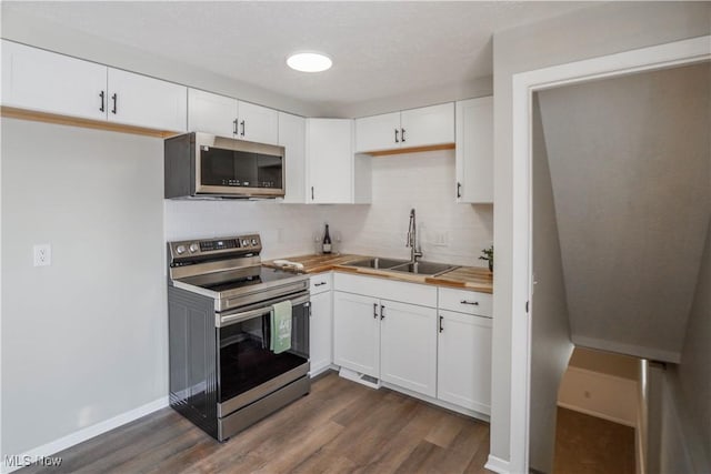 kitchen featuring butcher block countertops, sink, appliances with stainless steel finishes, white cabinets, and dark hardwood / wood-style flooring