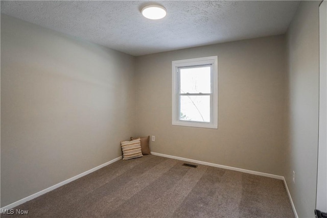 spare room with a textured ceiling and carpet