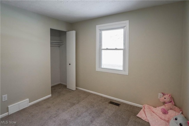 unfurnished bedroom with light colored carpet and a closet