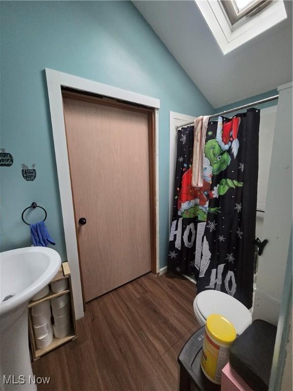 bathroom featuring a shower with shower curtain, wood-type flooring, and lofted ceiling with skylight