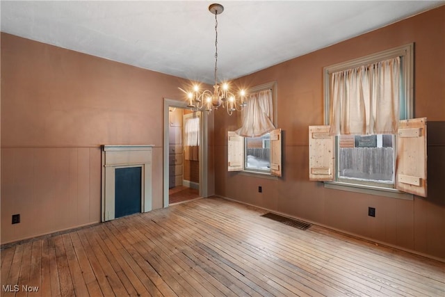 unfurnished dining area featuring a chandelier and light hardwood / wood-style floors