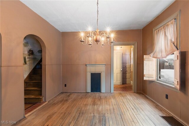 unfurnished dining area featuring a chandelier and light wood-type flooring