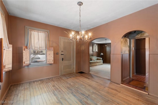 unfurnished dining area with light hardwood / wood-style floors and a notable chandelier