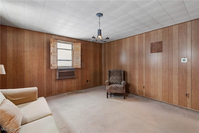 living area with light colored carpet, cooling unit, wooden walls, and a chandelier