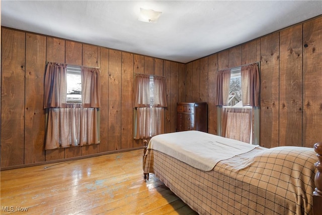 bedroom with light hardwood / wood-style floors and wood walls