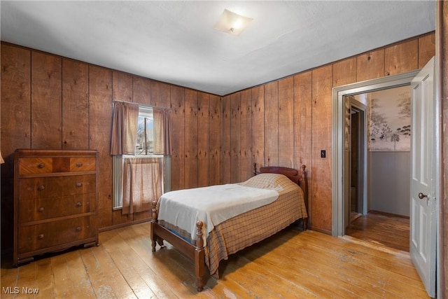 bedroom with light hardwood / wood-style floors and wood walls