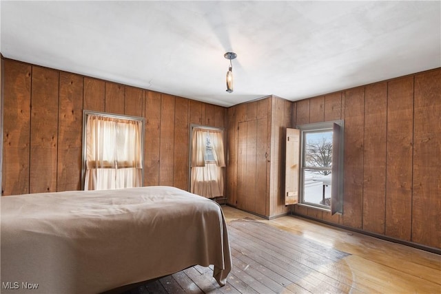 bedroom featuring light wood-type flooring and wood walls