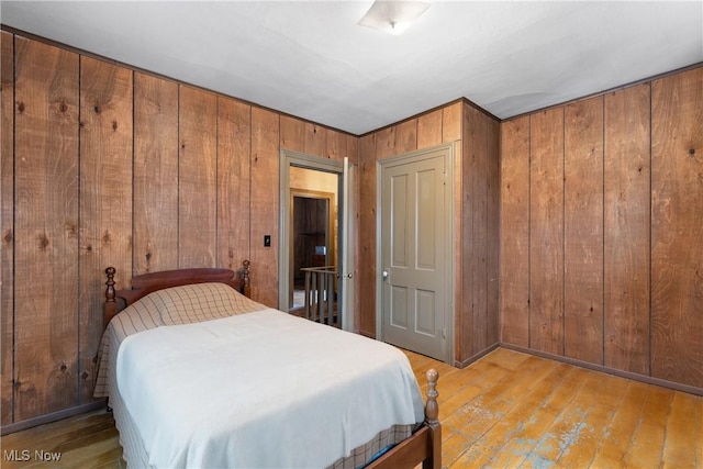 bedroom featuring wooden walls and light hardwood / wood-style flooring