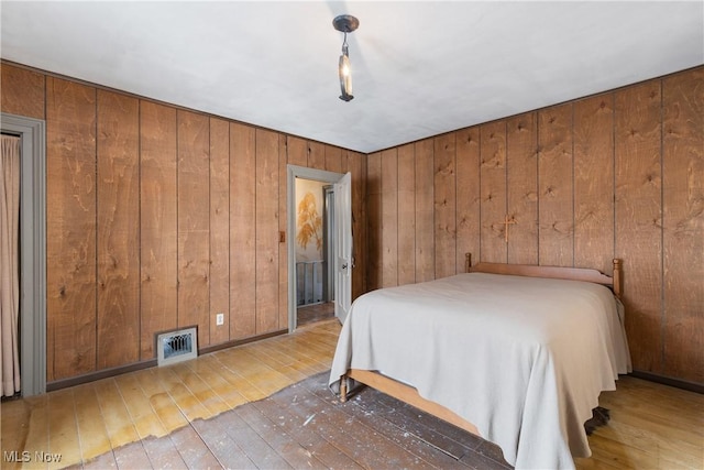 unfurnished bedroom with wooden walls and hardwood / wood-style flooring