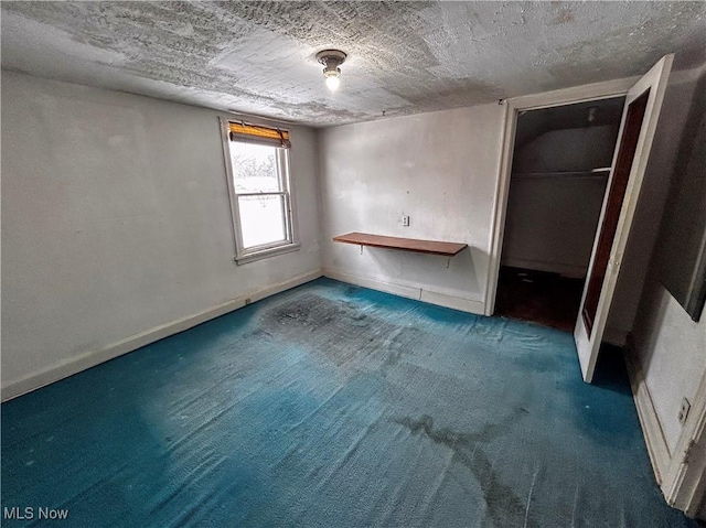 unfurnished bedroom featuring a closet, a textured ceiling, and dark colored carpet