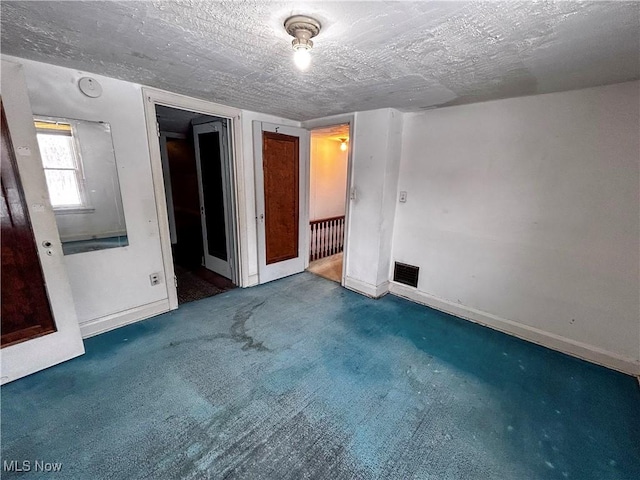 unfurnished bedroom featuring a textured ceiling and carpet