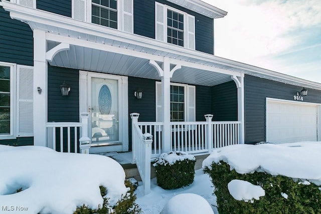 snow covered property entrance with a garage and a porch