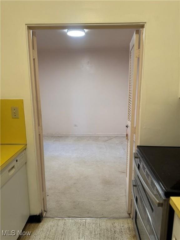 hallway with light colored carpet and baseboards