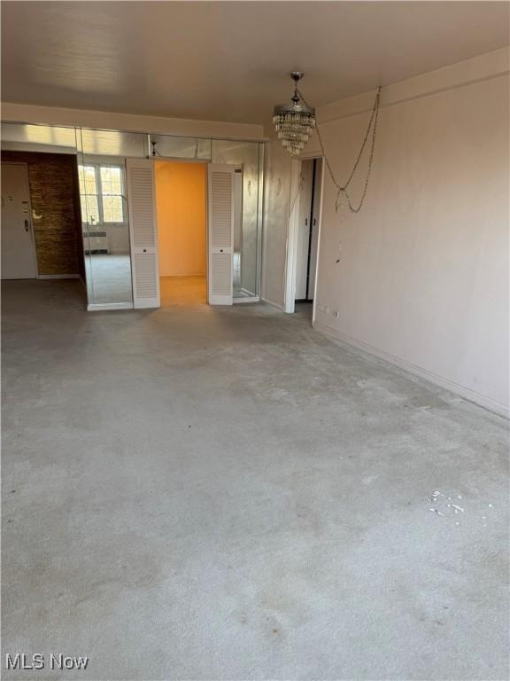 unfurnished room with concrete flooring and an inviting chandelier