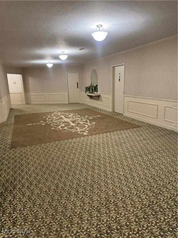 interior space with a decorative wall, wainscoting, and crown molding