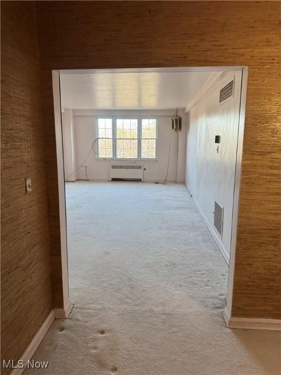 carpeted spare room with visible vents and radiator