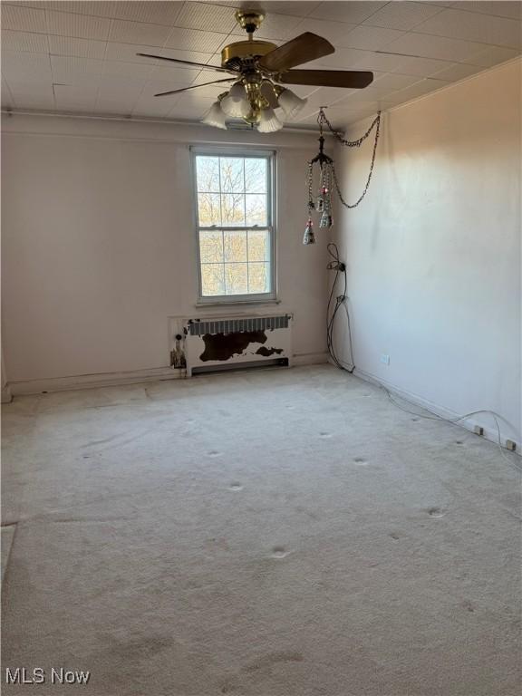 unfurnished room featuring radiator heating unit, a ceiling fan, and carpet floors