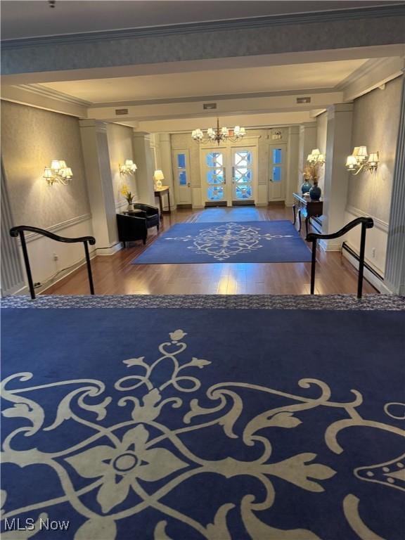 interior space with french doors, wood finished floors, ornamental molding, and a baseboard radiator