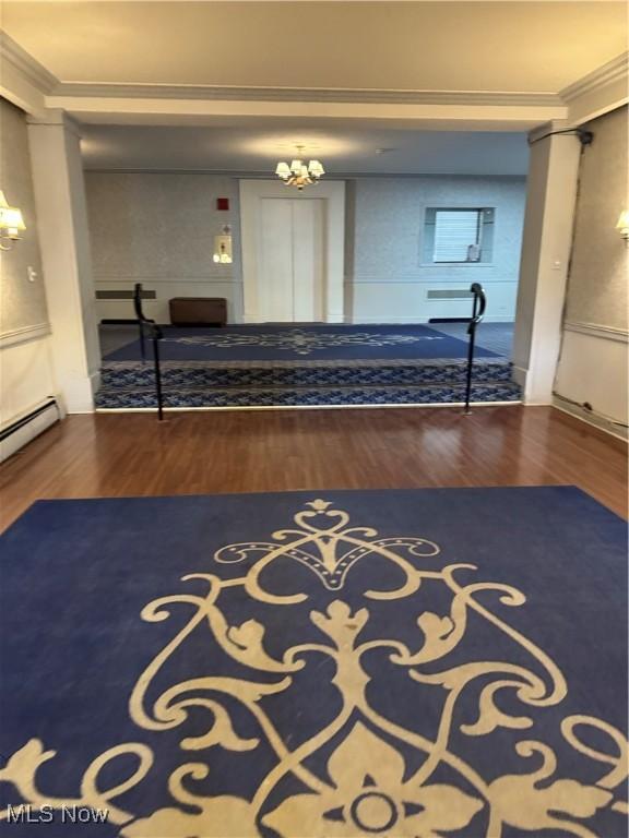 hall with decorative columns, wood finished floors, and crown molding