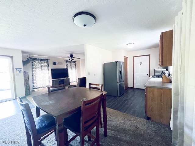 dining area featuring a ceiling fan, dark wood-style floors, and a textured ceiling