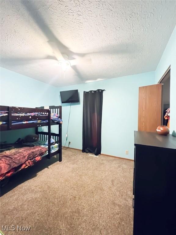 bedroom with a textured ceiling, a ceiling fan, and light carpet