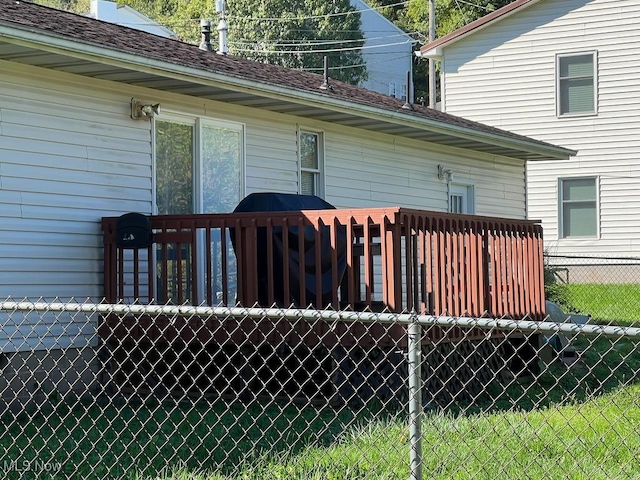 rear view of house featuring a shingled roof and fence