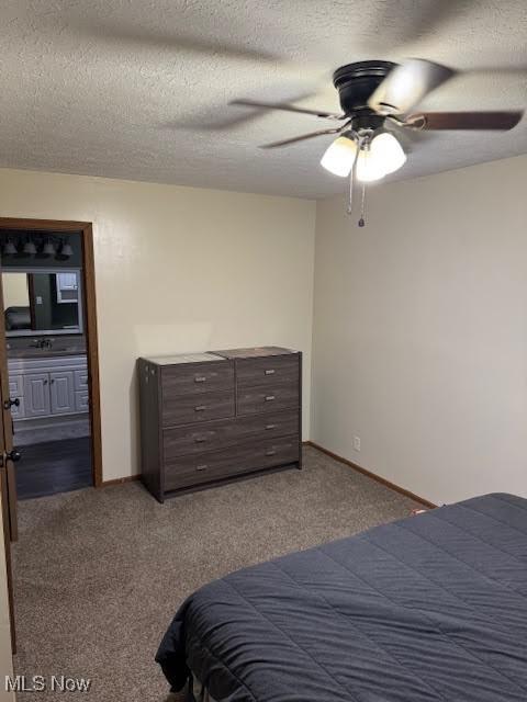 carpeted bedroom featuring a ceiling fan, baseboards, a sink, a textured ceiling, and connected bathroom