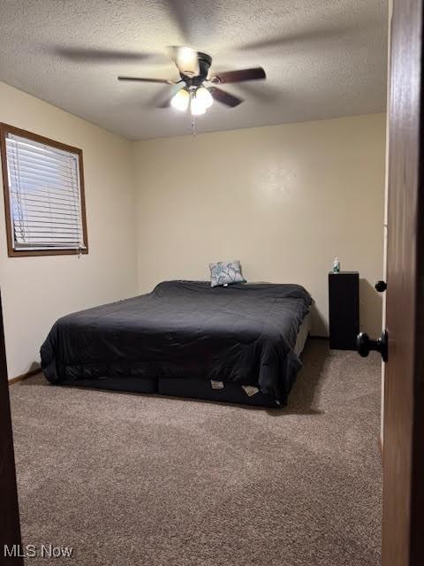 bedroom featuring carpet, a ceiling fan, and a textured ceiling