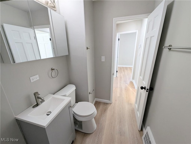 bathroom with toilet, vanity, and hardwood / wood-style floors