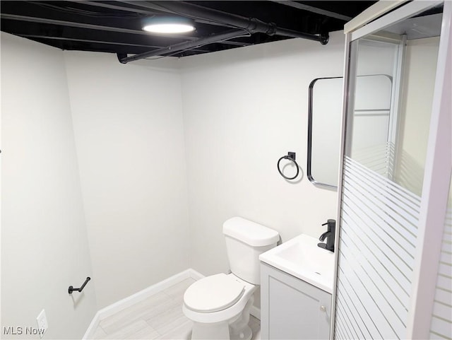 bathroom with toilet, hardwood / wood-style floors, and vanity