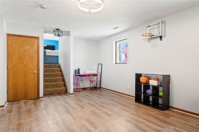 recreation room with wood-type flooring and a textured ceiling