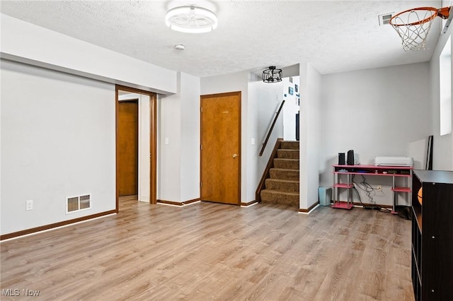 basement featuring a textured ceiling and light hardwood / wood-style flooring