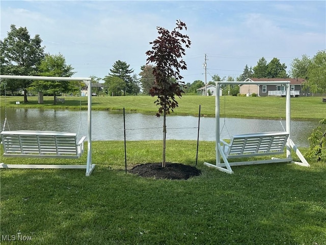 view of property's community with a water view and a lawn