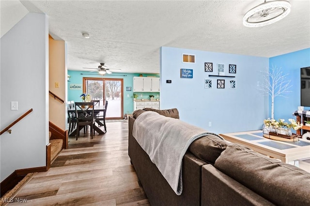 living room with ceiling fan, a textured ceiling, and hardwood / wood-style floors