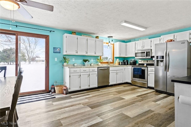 kitchen featuring a textured ceiling, stainless steel appliances, white cabinetry, and sink