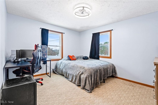 bedroom with a textured ceiling, light colored carpet, and multiple windows